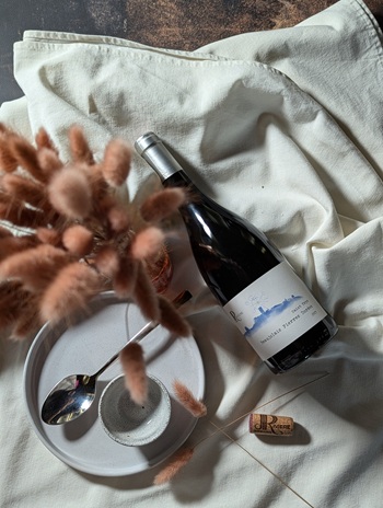 Bouteille de vin personnalisée du Domaine JP Riviere, cuvée Pierres Dorées, posée sur un linge en lin avec des fleurs séchées